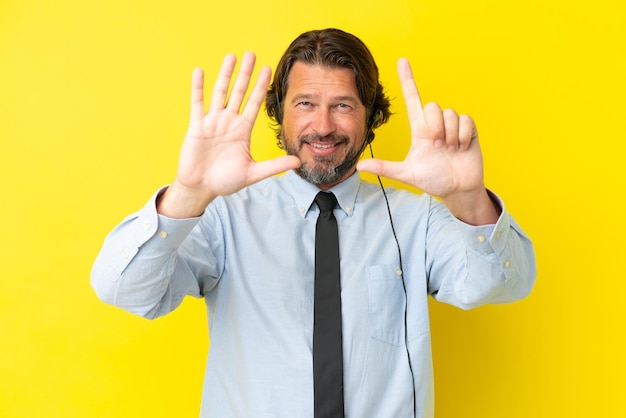 Homem holandês de telemarketing trabalhando com um fone de ouvido isolado em fundo amarelo contando sete com os dedos