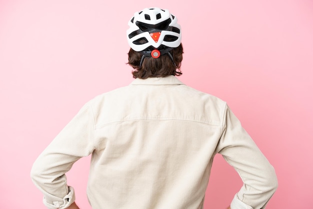 Homem holandês sênior com capacete de bicicleta isolado em fundo rosa na posição traseira