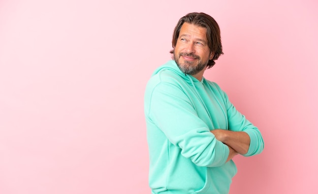 Homem holandês sênior isolado em fundo rosa com braços cruzados e feliz