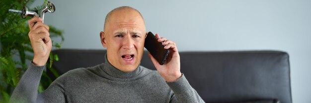 Homem homem mantém acessórios para móveis e falando no celular em casa.