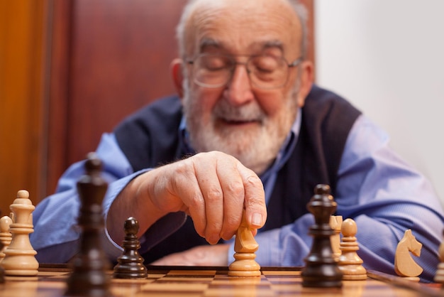 Homem idoso a jogar xadrez em casa.