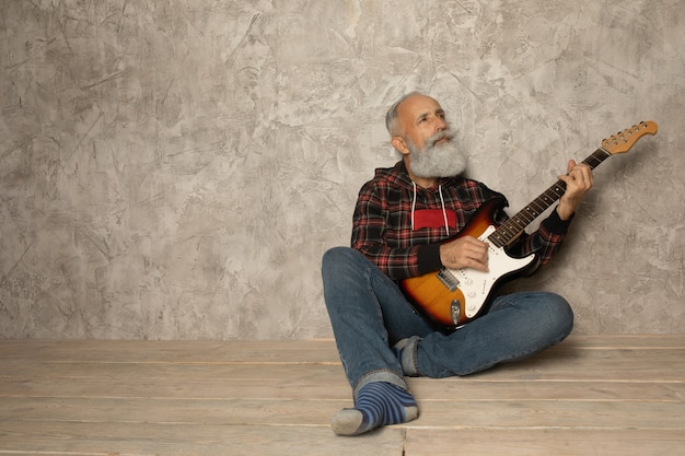 Homem idoso barbudo está tocando violão