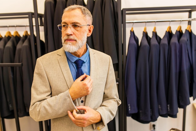 Homem idoso bonito em terno elegante e rico proprietário do estúdio atelier ocupado com o trabalho