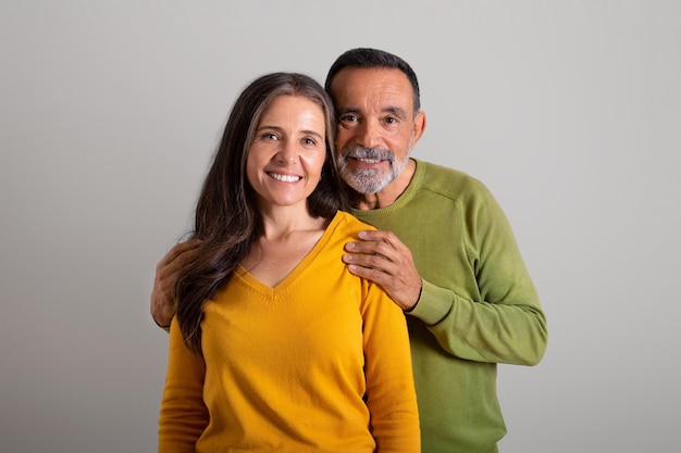 Homem idoso caucasiano feliz abraçando sua esposa aproveita o tempo livre e romântico no estúdio cinza