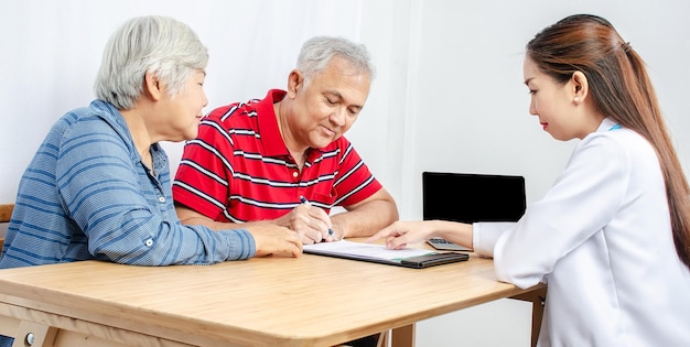 Homem idoso com mulher e médico escrevendo em papel na clínica