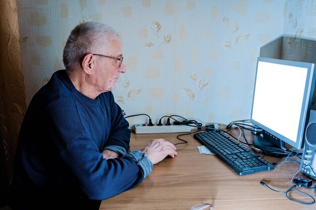 Homem idoso dos anos 80 em casa usando o pc.