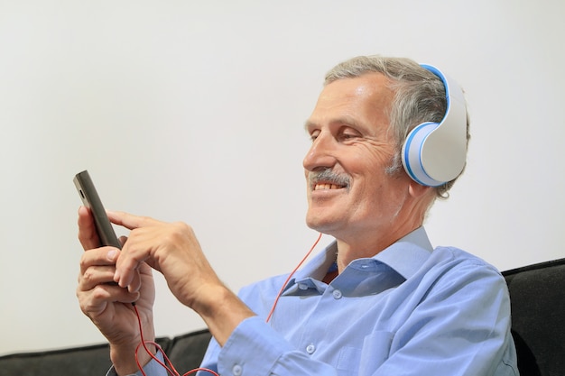 Homem idoso em fones de ouvido, ouvindo música