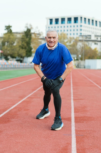 Homem idoso em forma desfruta de uma pausa na pista vestindo roupa esportiva com um sorriso brilhante permanecendo ativo