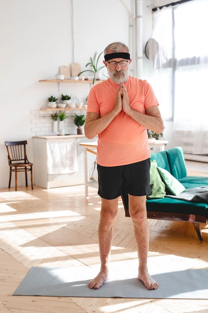 Homem idoso fazendo meditação idoso pensionista treinamento saudável saúde em casa