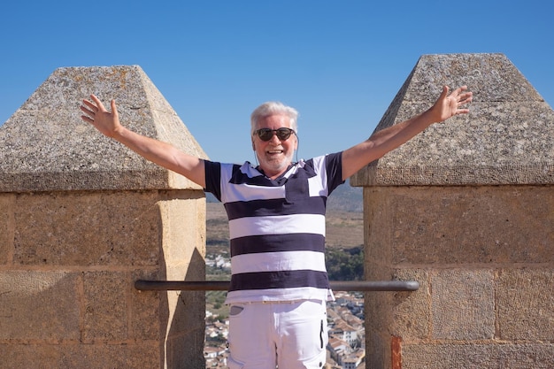 Homem idoso feliz com os braços estendidos visitando a Andaluzia, Espanha, olhando para a paisagem do alto