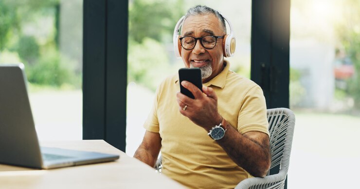 Foto homem idoso fones de ouvido e streaming de música no telefone playlist e assinatura em casa para áudio pessoa idosa laptop e leitura de notícias em aplicativo móvel podcast e canção de hip hop para diversão de fim de semana