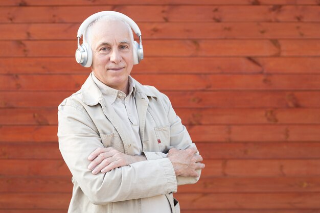 Homem idoso ouvindo música com fones de ouvido, sorrindo homem sênior com cabeça cinza, empresário bem sucedido.