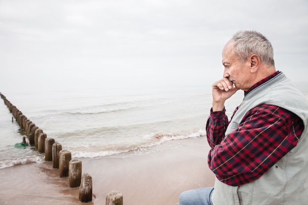 Foto homem idoso pensativo em pé na praia