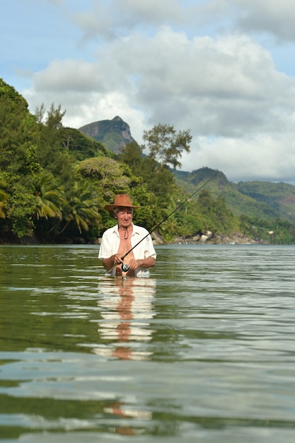 Homem idoso pescando no mar com uma vara de pescar