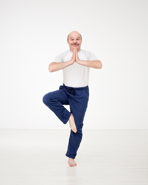 Homem idoso praticando ioga ou fitness humor positivo em atividades esportivas em pé asana de ioga