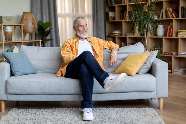 Homem idoso relaxado relaxando no sofá em casa