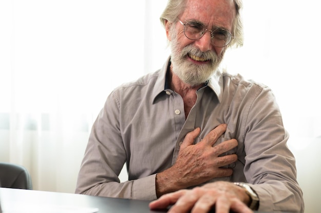 Foto homem idoso segurando a mão no peito e sofrendo de problemas cardíacos em casa