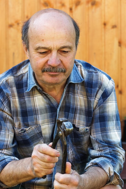 Homem idoso segurando um alicate na mão