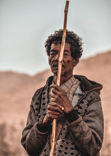 Foto homem idoso segurando um bastão de pé ao ar livre