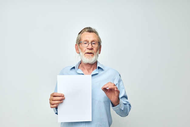 Homem idoso segurando uma folha de papel copyspace posando de fundo isolado