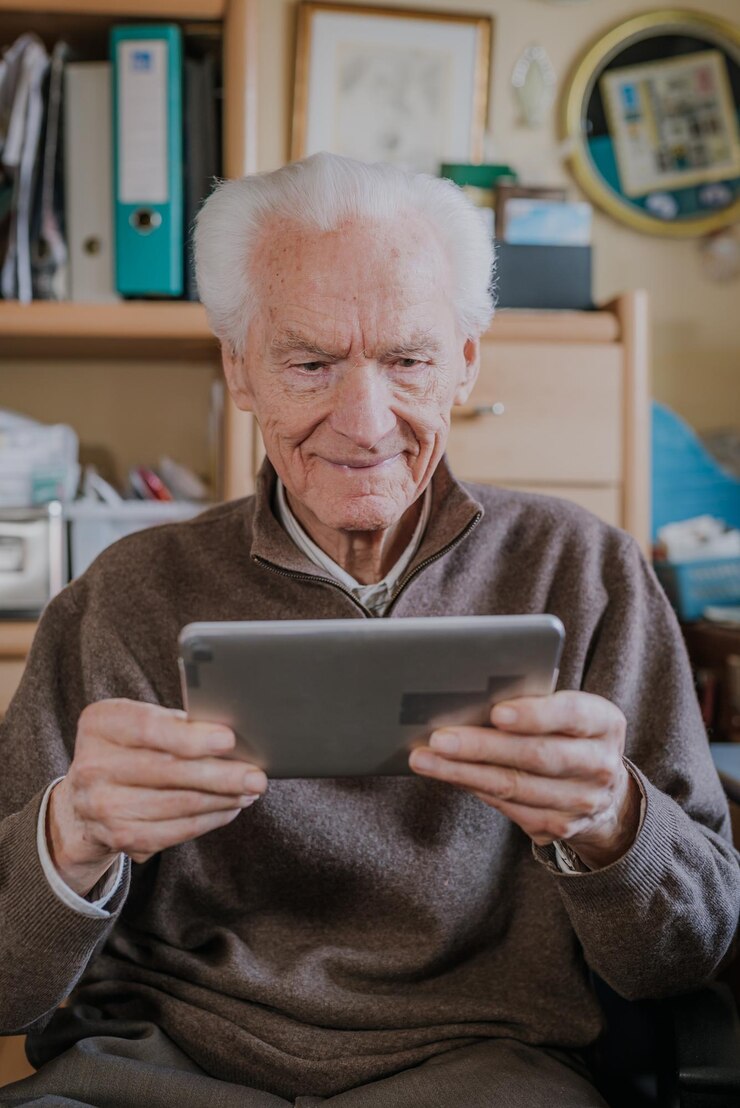 Foto homem idoso sorridente usando tablet digital em casa