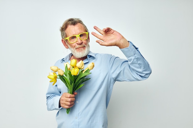 Homem idoso um buquê de flores com óculos como presente de fundo claro