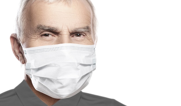 Homem idoso usando máscara facial durante epidemia de vírus isolada na parede branca