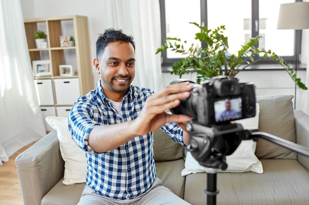 Foto homem indiano blogueiro de vídeo ajustando câmera em casa