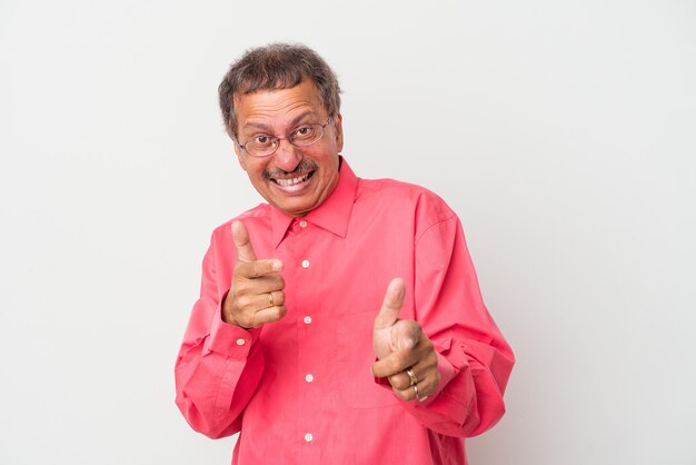 Homem indiano de meia idade isolado em sorrisos alegres de fundo branco, apontando para a frente.