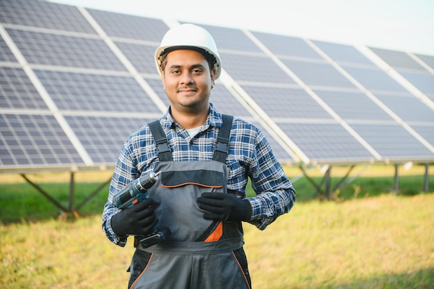 Homem indiano de uniforme em fazenda solar Engenheiro de energia competente controlando o trabalho de células fotovoltaicas