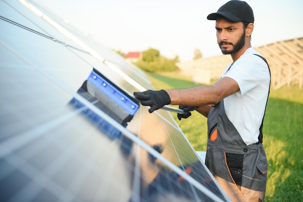 Homem indiano de uniforme trabalhando perto de painel solar