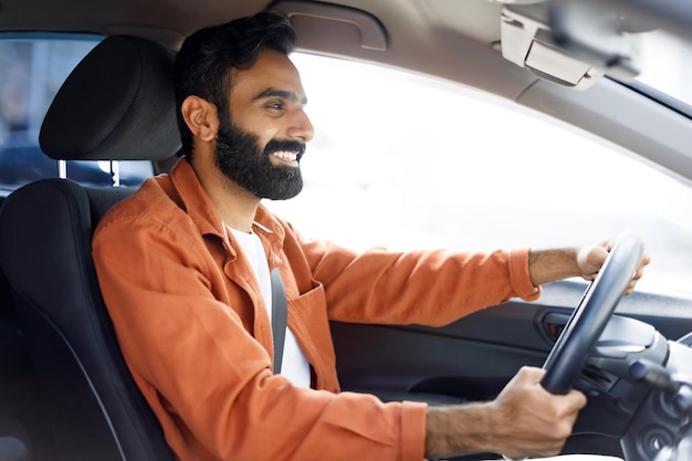 Homem indiano dirigindo desfrutando de um novo veículo moderno sentado no automóvel