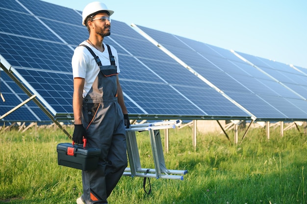 Homem indiano em uniforme trabalhando perto do painel solar