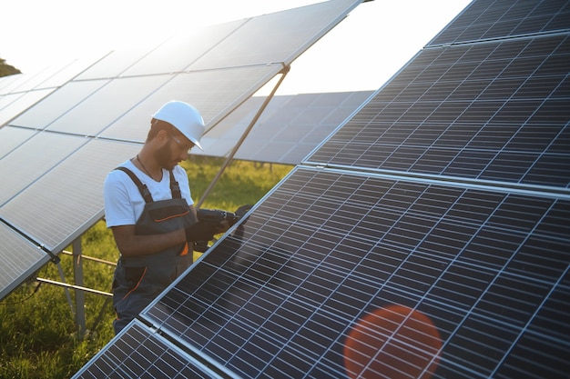 Homem indiano em uniforme trabalhando perto do painel solar