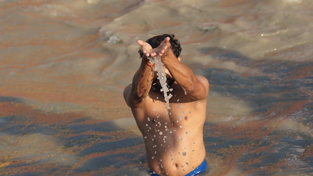 Homem indiano fazendo suryanamaskar no rio ganga