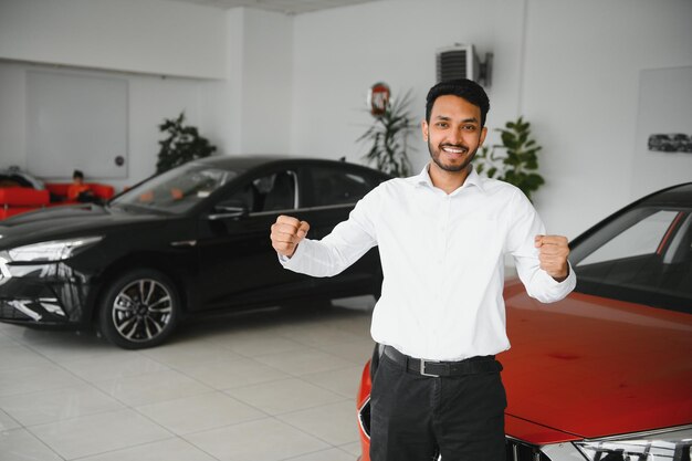 Foto homem indiano feliz compra novo automóvel ecológico de biodiesel no showroom de luxo