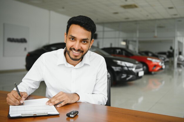 Homem indiano feliz compra novo automóvel ecológico de biodiesel no showroom de luxo