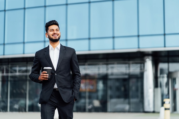 Homem indiano feliz e bem-sucedido, empresário, sorrindo e feliz indo para uma reunião de negócios