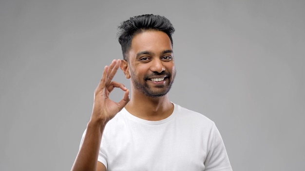 homem indiano feliz em camisa mostrando o sinal da mão ok