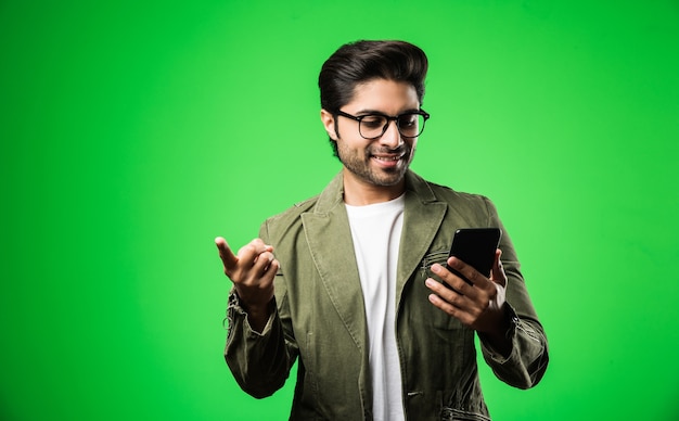 Homem indiano ou asiático com smartphone, usando telefone celular em pé isolado