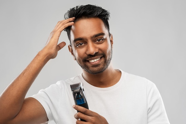 homem indiano sorridente com cortador tocando seu cabelo