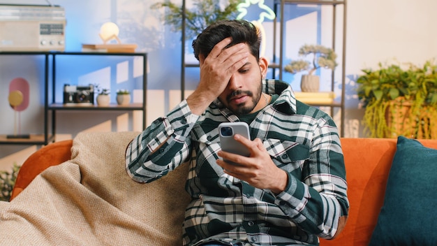 Homem indiano triste usa smartphone surpreendido por más notícias perda de fortuna falha resultados da loteria prazo