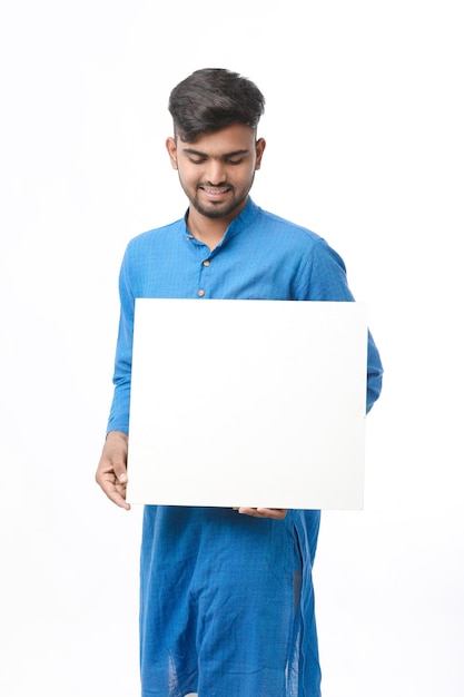 Homem indiano vestindo panos tradicionais e mostrando a placa no fundo branco.