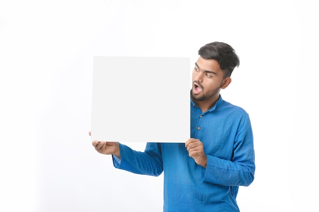 Homem indiano vestindo panos tradicionais e mostrando a placa no fundo branco.