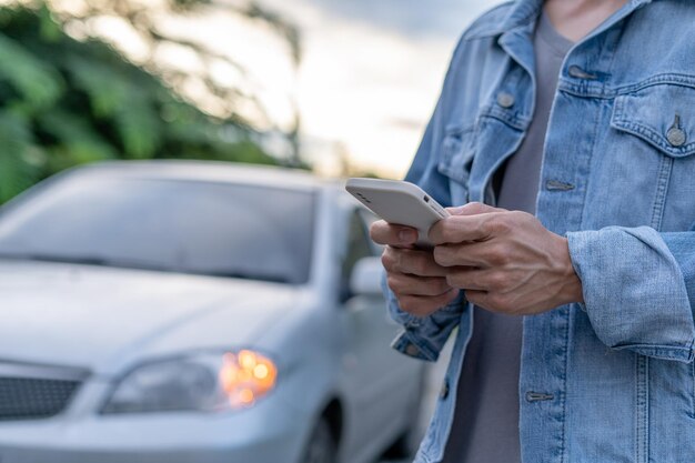 Homem informa para obter ajuda devido a um carro de emergência através de um sistema de aplicativo móvel Um homem procura uma garagem para consertar seu carro durante um passeio rural Avaria do carro e conceito de seguro de carroxDxA