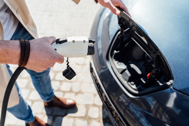 Homem insere o plugue no carro elétrico