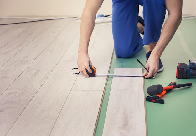 Homem instalando novo piso laminado de madeira