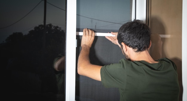 Homem instalando o mosquiteiro na janela