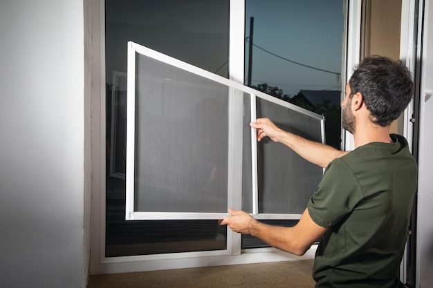 Homem instalando o mosquiteiro na janela