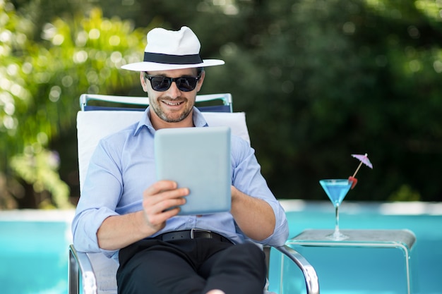 Homem inteligente usando tablet digital perto da piscina